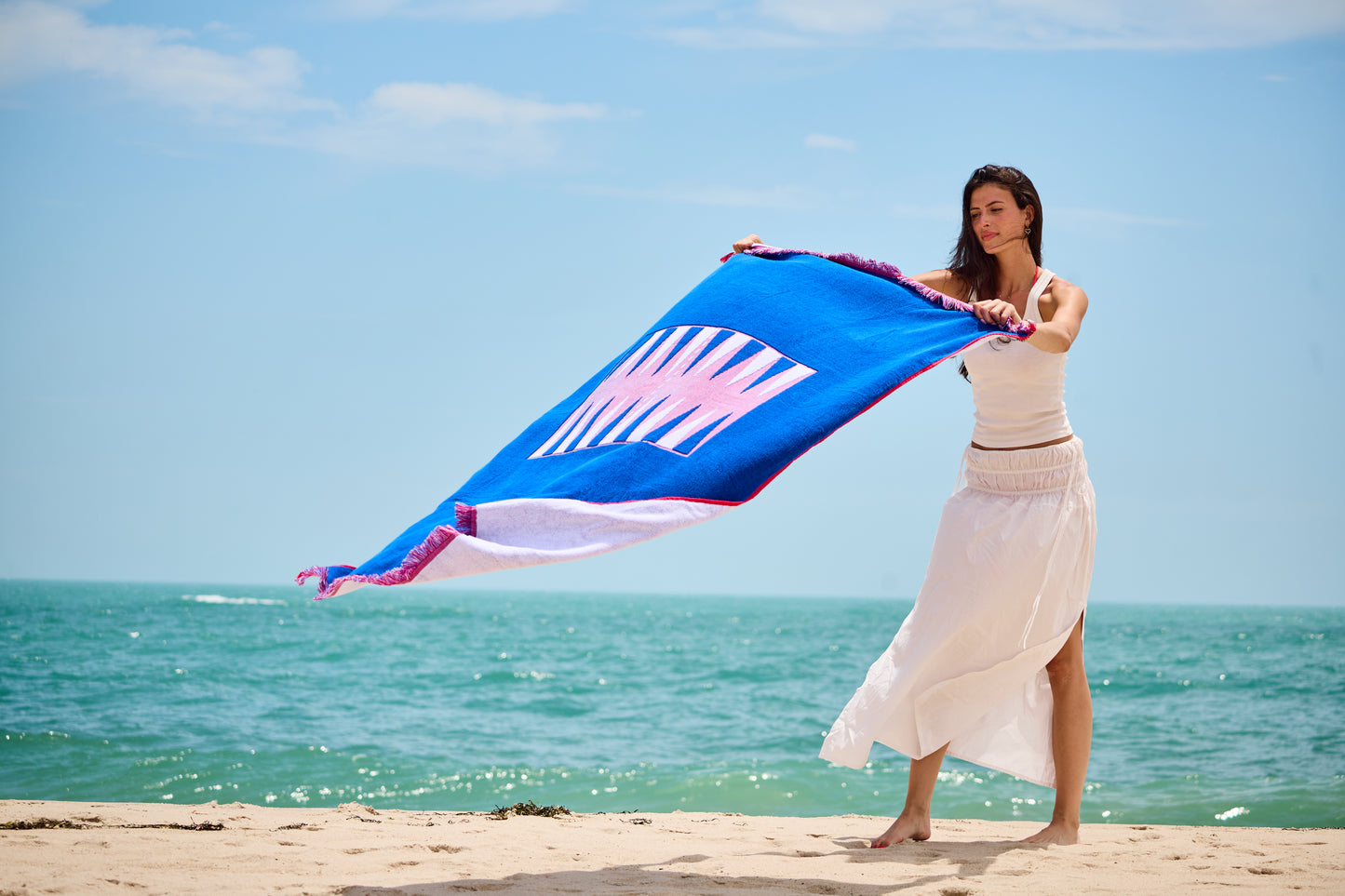 Woman at the beach on a sunny day laying out the Beach Board - blowing in the wind