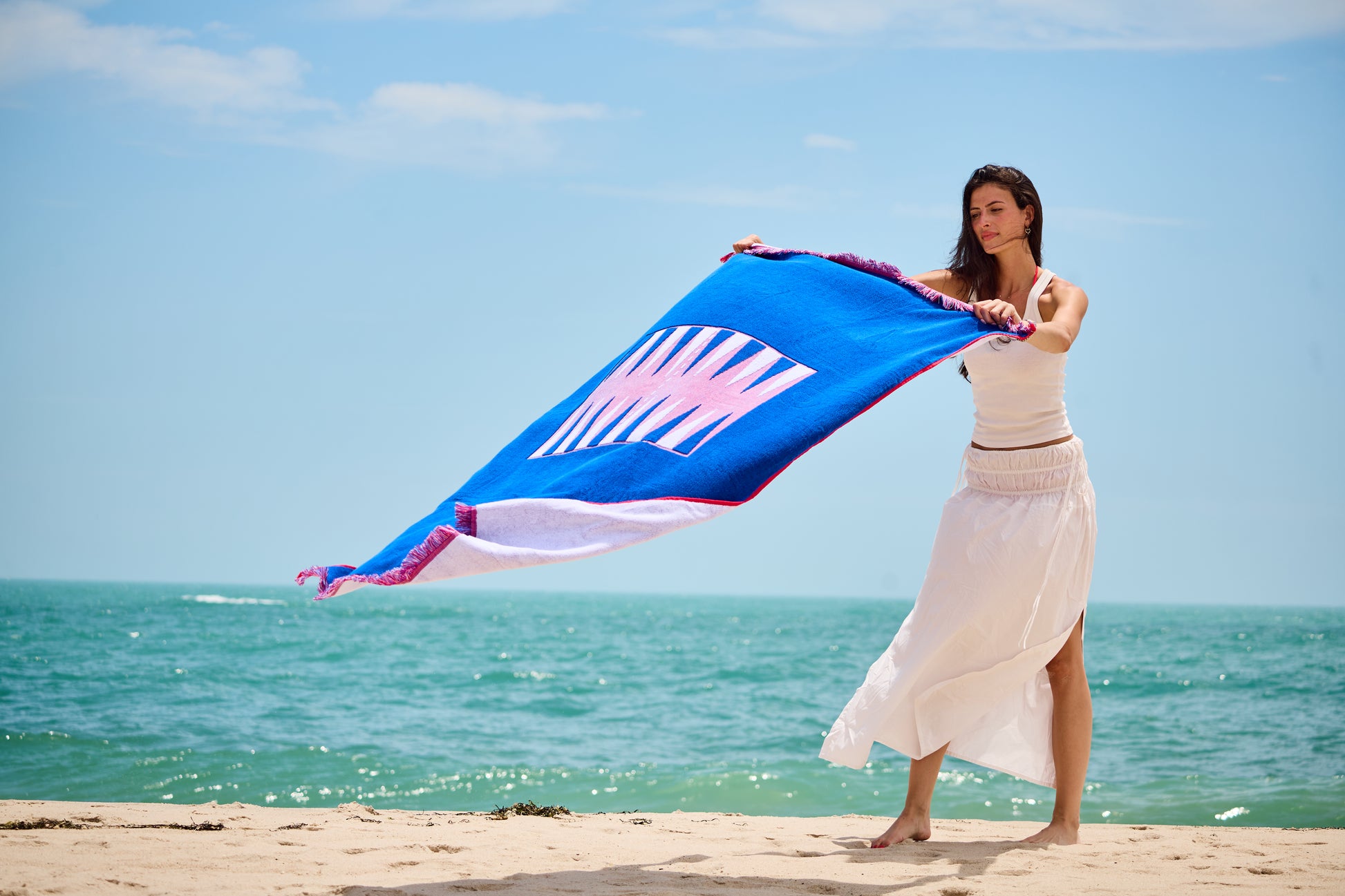 Woman at the beach on a sunny day laying out the Beach Board - blowing in the wind