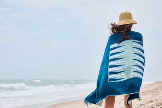 Woman walking on beach with Comporta Beach Board wrapped around her