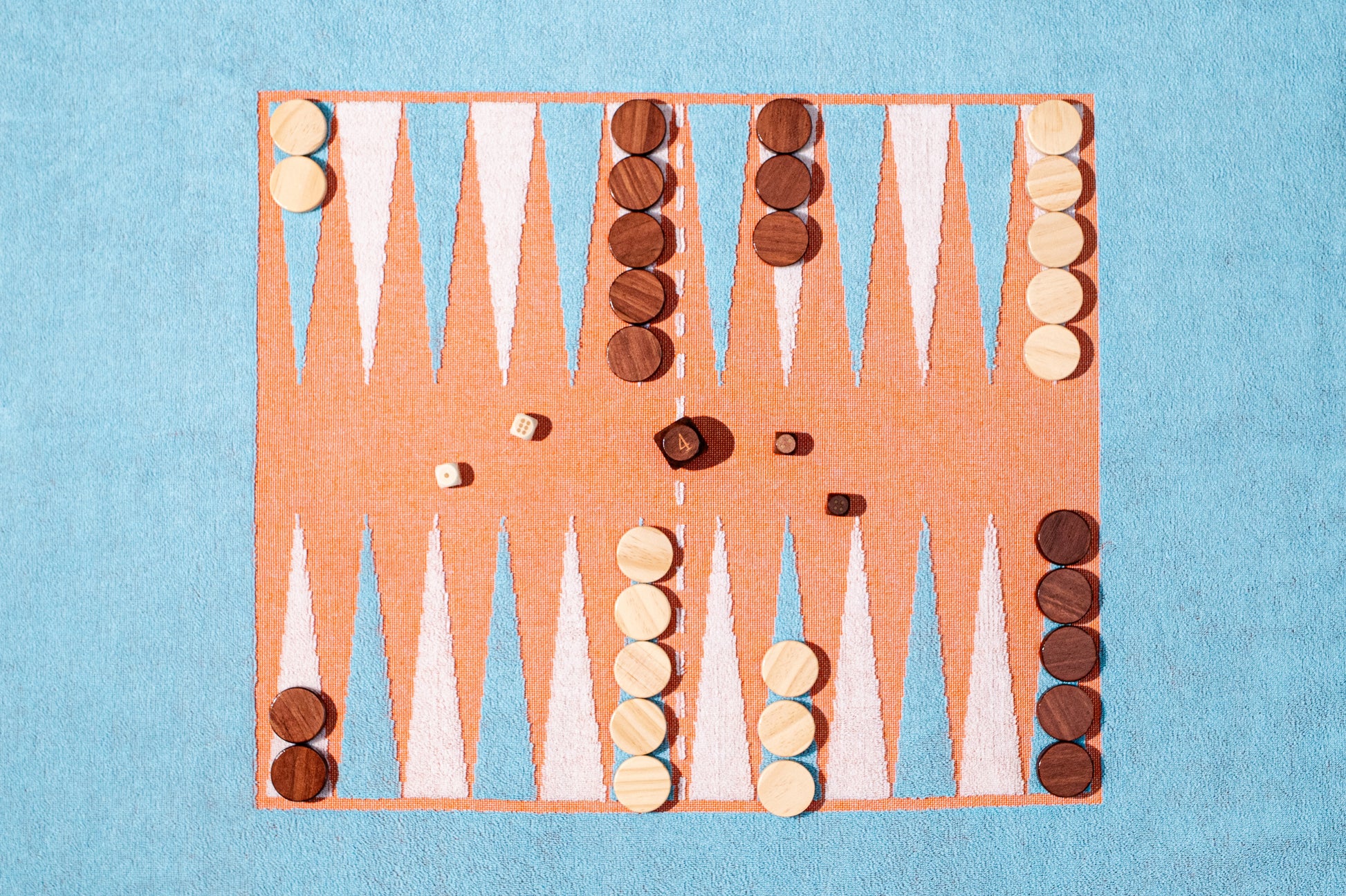 Close up of backgammon board on towel set with wood pieces and dice, ready for play