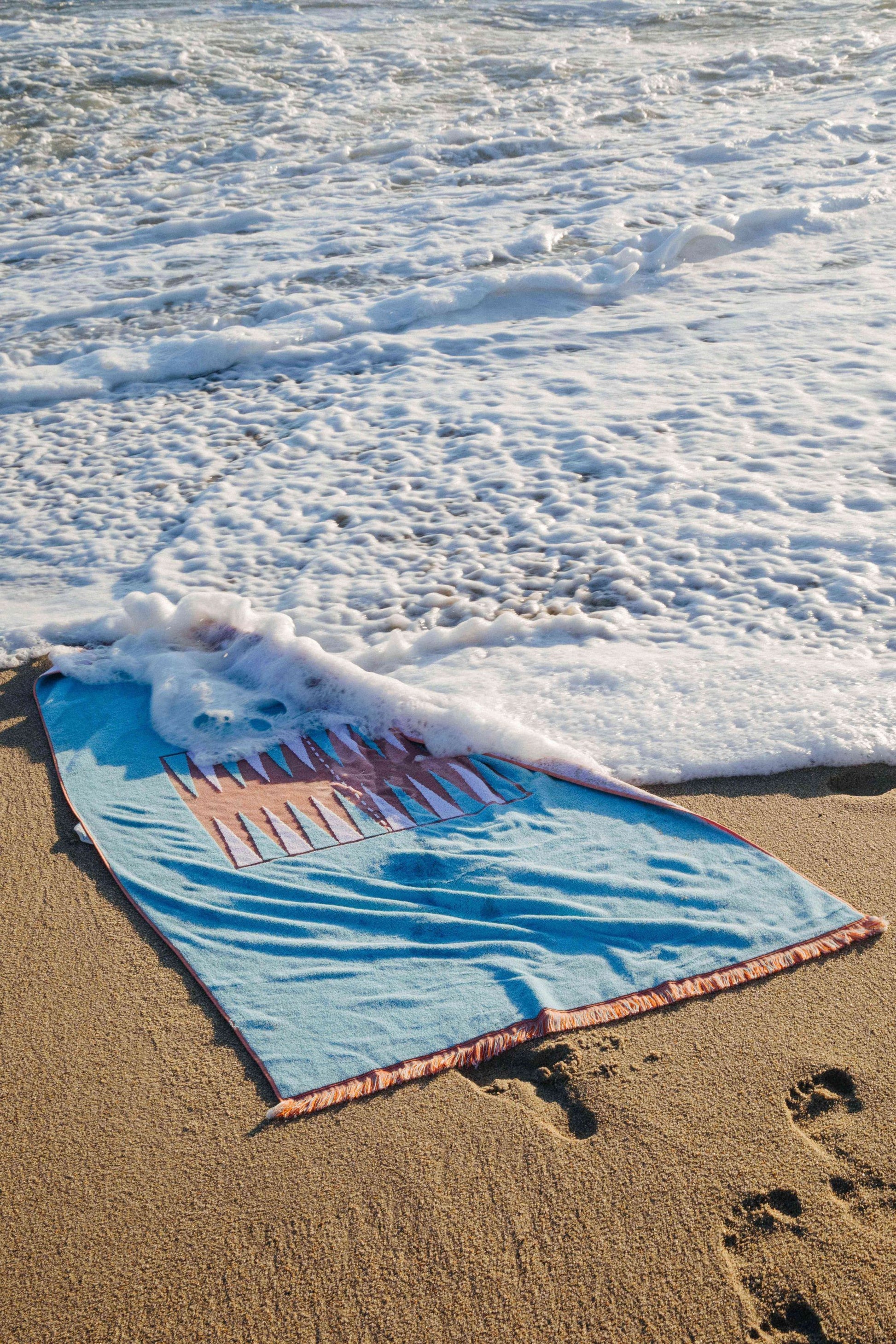 Artistic photo of blue and orange beach board in the foamy water of the ocean