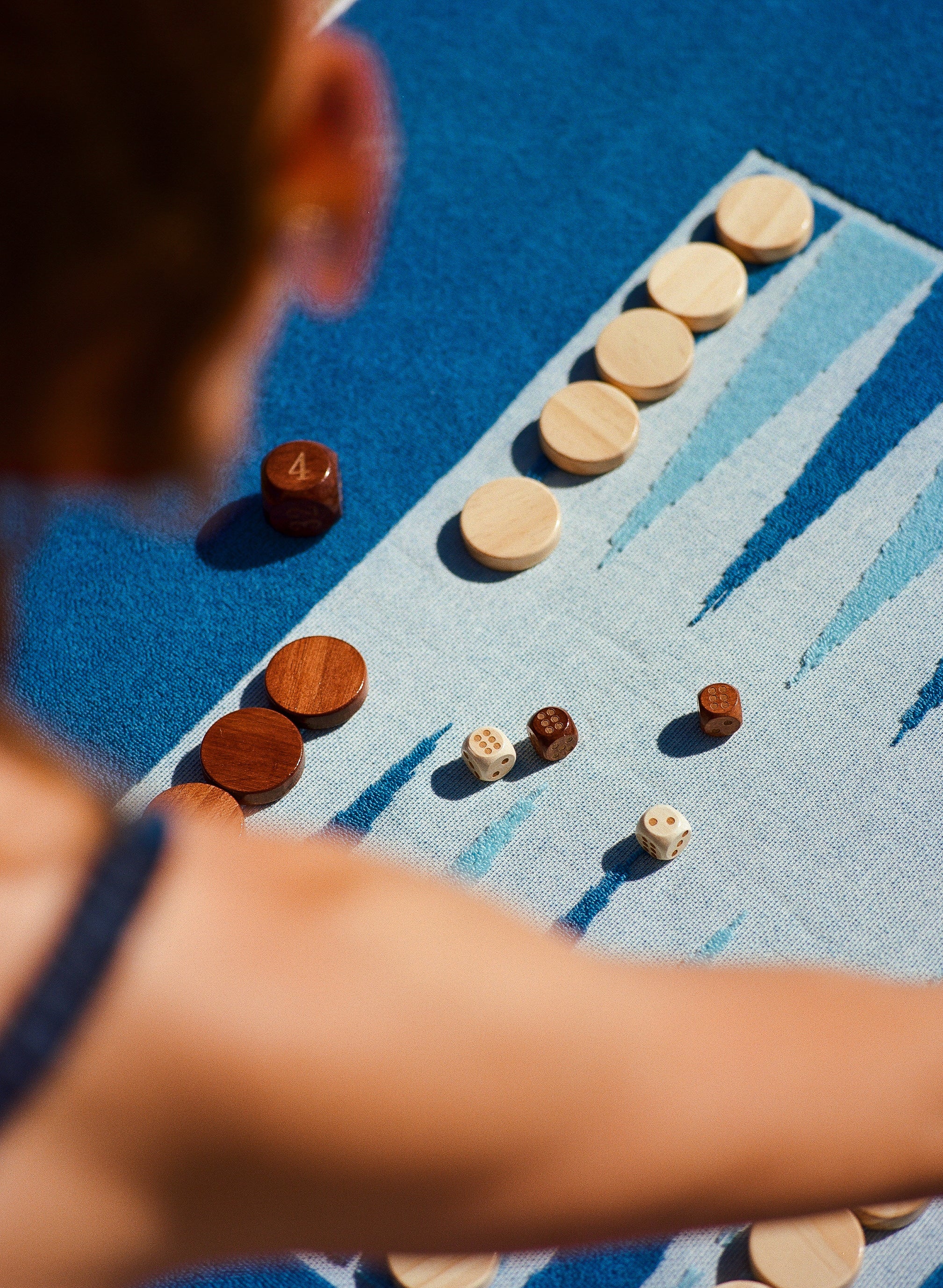 Over the shoulder vantage point focused on the backammon pieces placed on the Beach Board